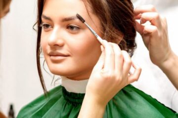 Femme appliquant une pâte de henné sur ses cheveux à la maison devant un miroir.